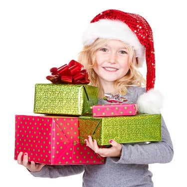 Young girl wearing Santa cap while holding a stack of colorfully wrapped Christmas gifts