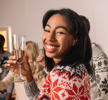 Pretty young lady holding a champagne glass as she socializes at a Christmas party